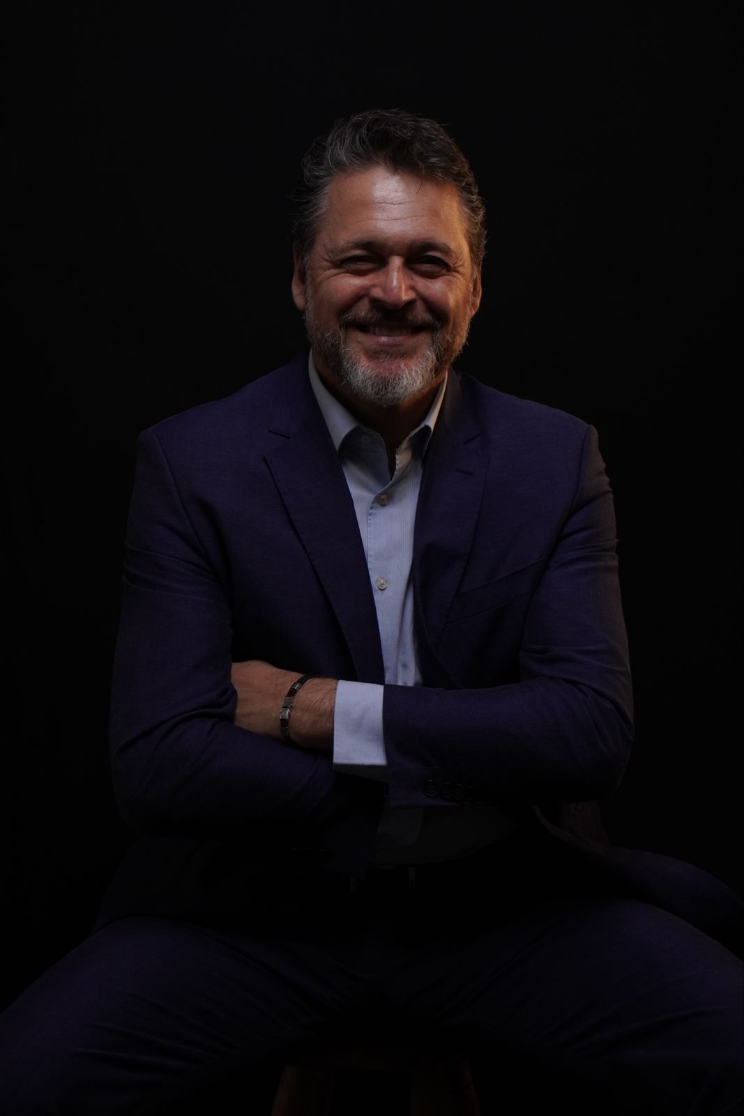 Mario Miozzo sorrindo, sentado em estúdio
